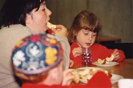 [Two children and a woman eating apples and honey]