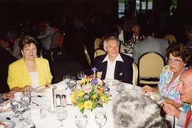 [Unknown people sitting around a table at an unknown event smiling for the camera]