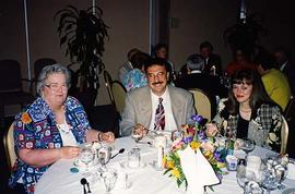 [Two unknown women and an unknown man sitting at a table at an unknown event]