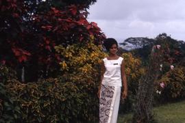 Woman dressed in white standing in front of a garden