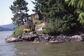 Wooden houses on a rocky and tree-lined shore surrounded by water