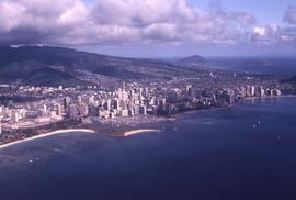 City-scape with water in the foreground and mountains and clouds in the background