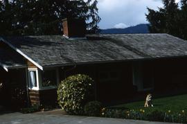 Side of the Snider's home, with a one of the Snider's dogs sitting on grass in front of the house