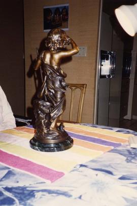 [Back side of a bronze statue which is resting on a table]