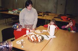 [Group of children and a woman eating challah, apples and honey]