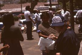 Phyliss Snider with a paper and plastic bag in her hand and a woman with a baby sling looking on