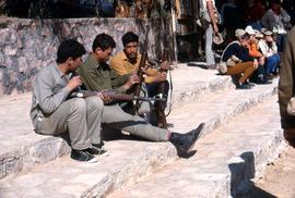 Three unidentified men (soldiers?) sitting on stone steps, holding guns