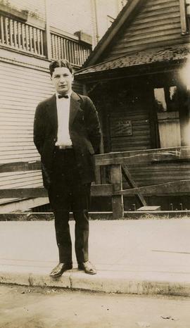 [Young Irving Snider posing for the camera with a house behind him]