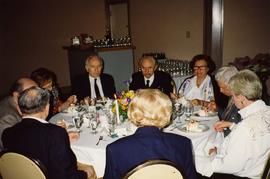 [Group of unknown people sitting around a table eating]