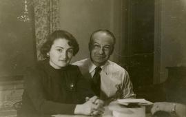 [Dr. Irving and Phyliss Snider sitting at a table and posing for the camera in their home in Whyt...