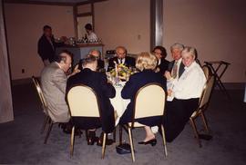 [Group of unknown people sitting at a table eating]