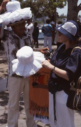 Phyliss Snider buying a white hat from a man with several white hats on his head