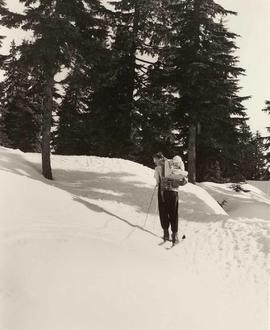 Woman on cross country skis, carrying baby on back board