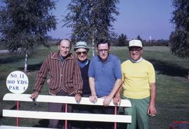 Four unknown men posing behind a bench on a golfcourse