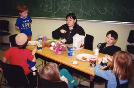 [Group of children and woman eating]