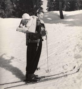 Woman on cross country skis, carrying baby on back board