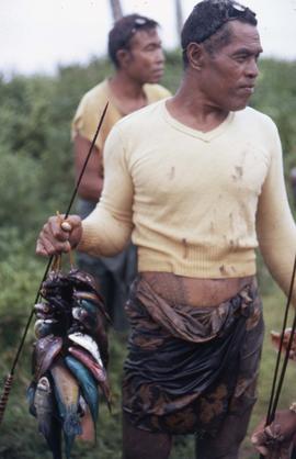 Fisherman holding up fish on a stick