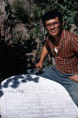 A stone cutter working on a couple of tombstones