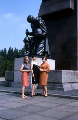 Three unidentified women standing in front of a monument