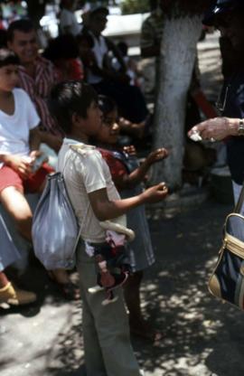 Phyliss Snider handing something to two children with people looking on in the background