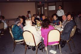 [Dr. Irving and Phyliss Snider sitting with a group of unknown people at a table eating]