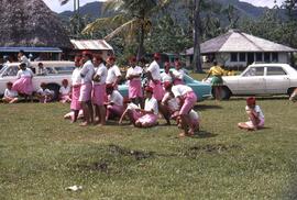 Group of people assembled on a lawn in uniform consisting of pink lava-lavas and white shirts