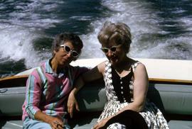 Two unknown women wearing sunglasses sitting on the back of a boat