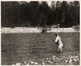 Man fishing thigh deep in water