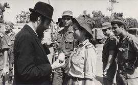 A Lubavitch youth instructs Israeli soldiers in the performance of the 'lulav' and 'etrog' mitzvah