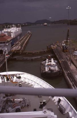 Metal bar and the bow of a boat with water, docks and boats in the background