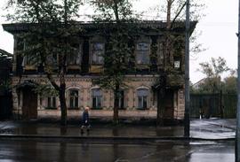 Woman in a blue coat walking past a two-story building