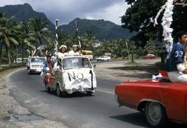 Group of people celebrating a sports victory by driving along a street with banners and players i...