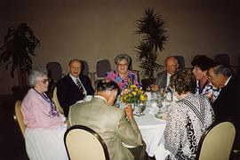 [Unknown people at an unknown event sitting around a table talking]