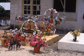 Grave with flowers laid around it and identified by a cross with the name "Marlene" wri...